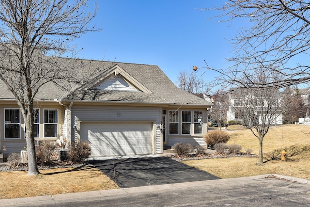 view of front of property featuring a garage, a front lawn, roof with shingles, and driveway