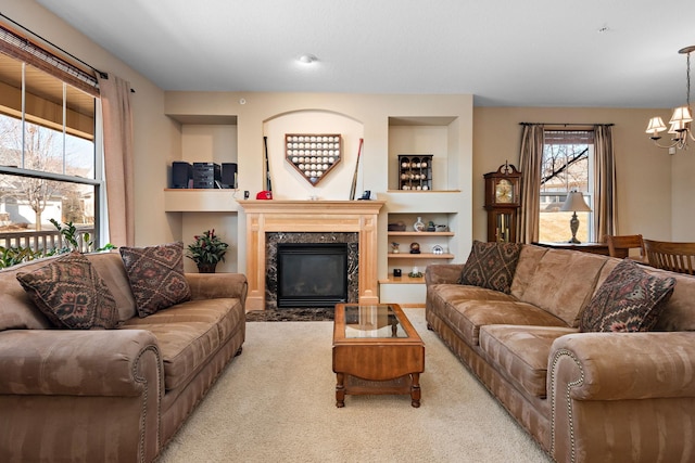 carpeted living room with an inviting chandelier, built in features, and a fireplace