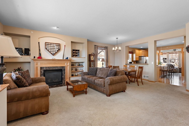 carpeted living room featuring an inviting chandelier, plenty of natural light, a fireplace, and visible vents