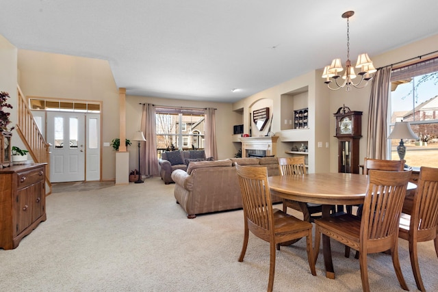 dining area with light carpet, an inviting chandelier, and a fireplace