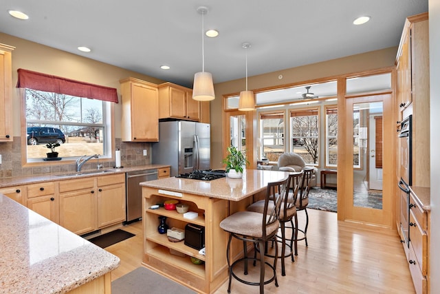 kitchen featuring a kitchen island, light brown cabinets, stainless steel appliances, and a sink