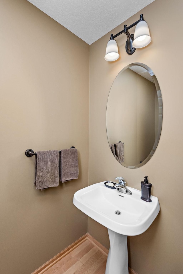 bathroom with a sink, a textured ceiling, baseboards, and wood finished floors