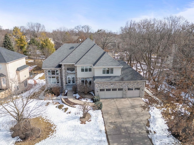 traditional-style home with stone siding, roof with shingles, concrete driveway, and an attached garage