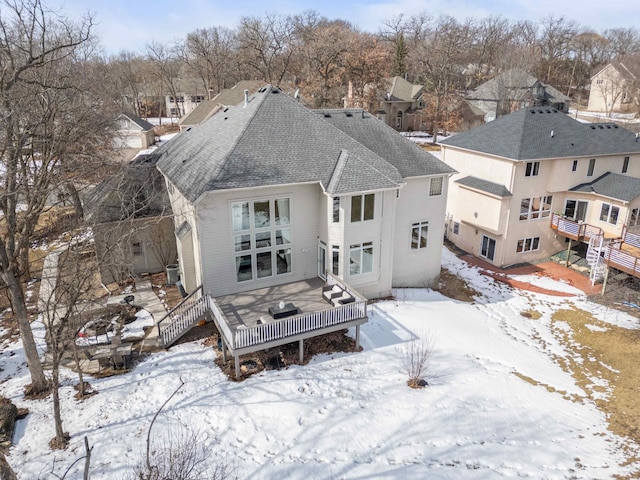 snow covered rear of property with a wooden deck, central AC, and a shingled roof