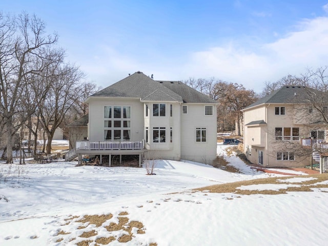 snow covered rear of property with a wooden deck