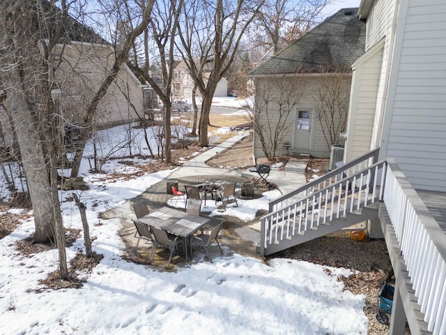 snowy yard featuring outdoor dining area and a patio