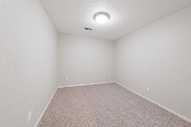 empty room with baseboards, visible vents, carpet floors, a textured ceiling, and a textured wall