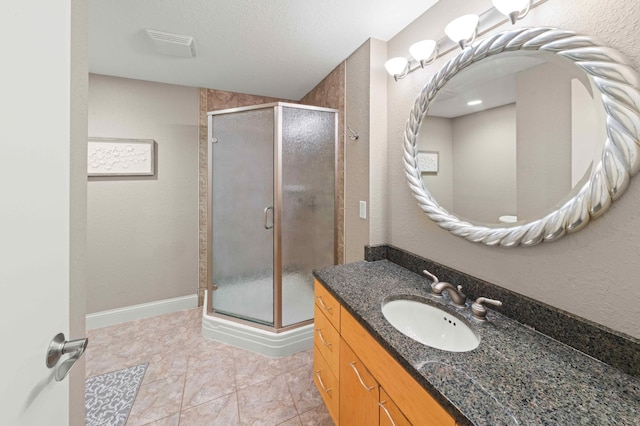 bathroom featuring vanity, baseboards, a shower stall, a textured ceiling, and tile patterned floors