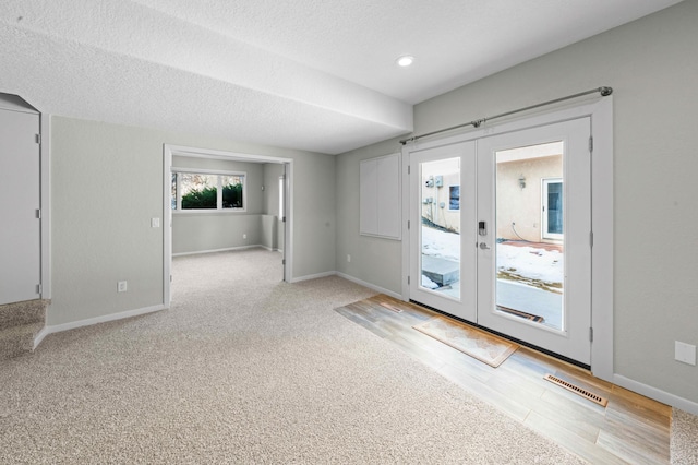 interior space with visible vents, baseboards, a textured ceiling, and french doors