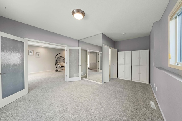 interior space with carpet flooring, visible vents, french doors, and baseboards