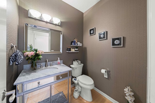 bathroom with baseboards, toilet, wood finished floors, and vanity