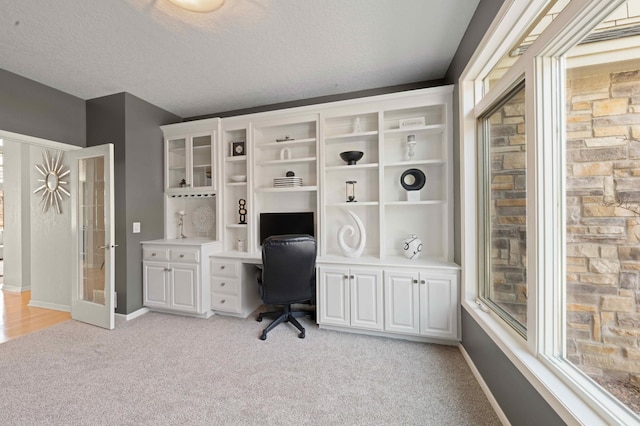 office area featuring light colored carpet, a textured ceiling, and baseboards