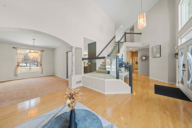 foyer entrance featuring a notable chandelier, stairway, wood-type flooring, arched walkways, and baseboards