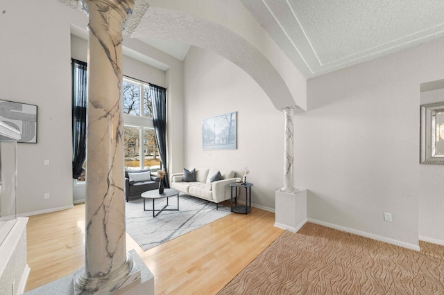 interior space with decorative columns, arched walkways, baseboards, and wood finished floors