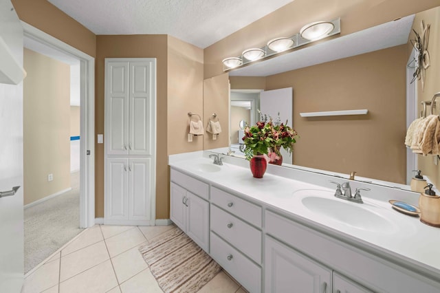 full bath featuring a sink, a textured ceiling, double vanity, and tile patterned floors