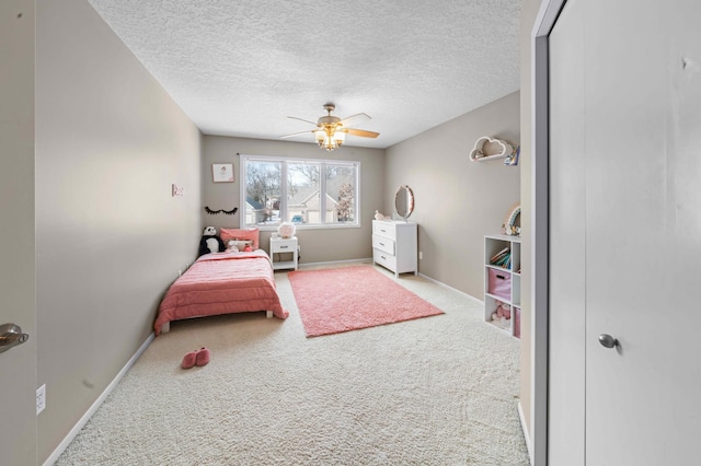 carpeted bedroom with a ceiling fan, baseboards, and a textured ceiling