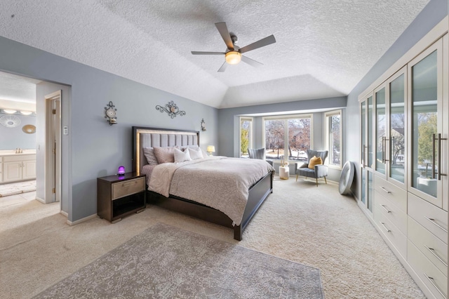 bedroom with carpet flooring, baseboards, lofted ceiling, and a sink