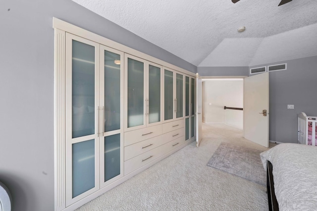 bedroom featuring carpet floors, a textured ceiling, visible vents, and vaulted ceiling