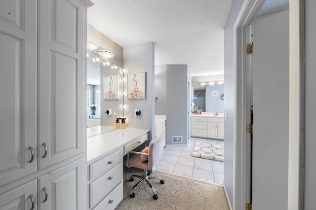 bathroom with vanity, baseboards, visible vents, a textured ceiling, and tile patterned floors