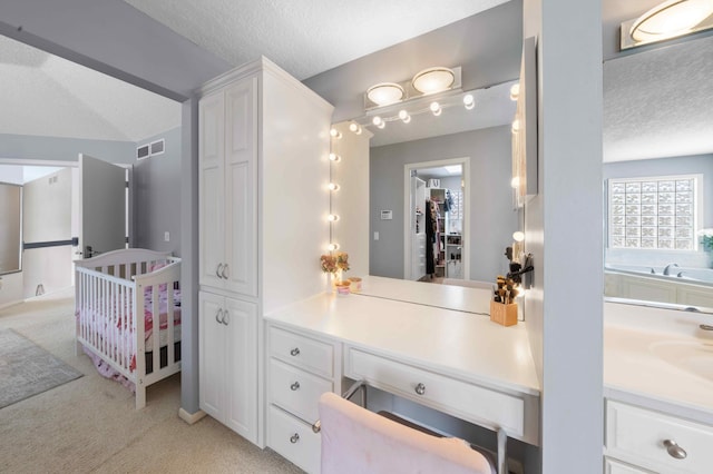 bathroom with a closet, visible vents, a textured ceiling, and vanity