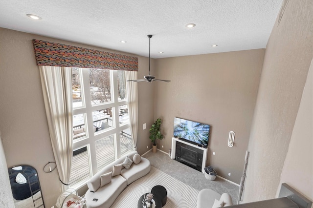 carpeted living room with a glass covered fireplace, recessed lighting, a textured ceiling, and baseboards