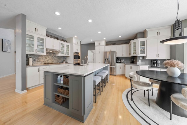 kitchen with under cabinet range hood, light wood finished floors, appliances with stainless steel finishes, and a sink