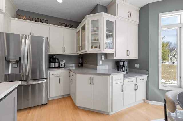 kitchen featuring light wood-style floors, stainless steel refrigerator with ice dispenser, and light countertops