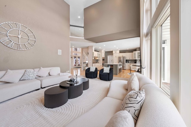 living area with recessed lighting, light wood-style floors, and a towering ceiling