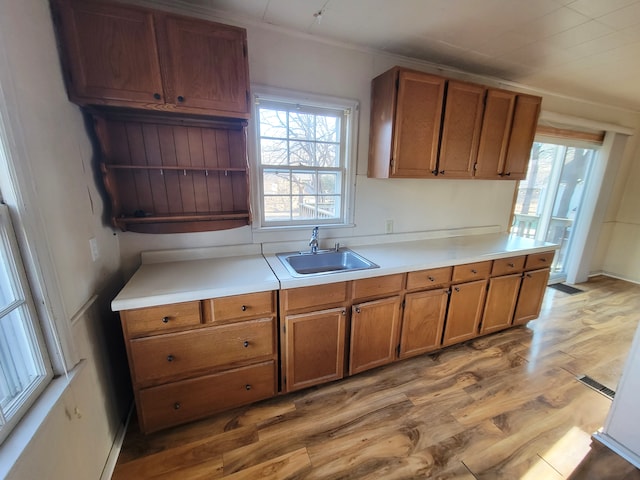 kitchen with light countertops, light wood-style floors, brown cabinets, and a sink