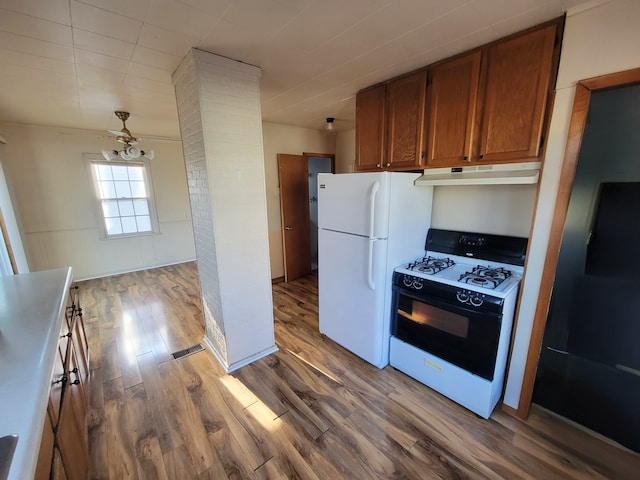 kitchen with under cabinet range hood, brown cabinets, freestanding refrigerator, wood finished floors, and gas stove