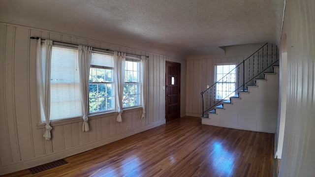 entryway with visible vents, a textured ceiling, stairs, and wood finished floors