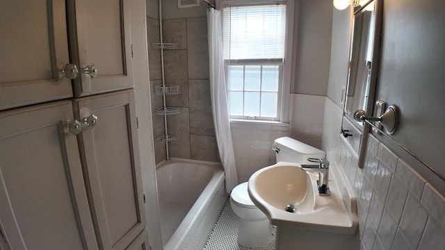 full bathroom with toilet, a sink, tile walls, wainscoting, and shower / tub combo