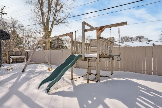 snow covered playground with a fenced backyard and a playground