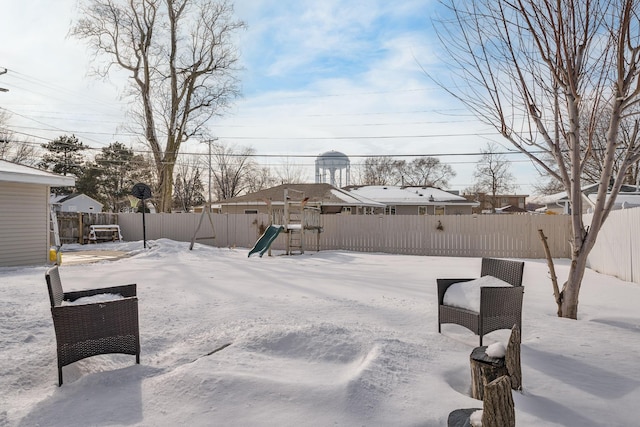 yard covered in snow featuring a fenced backyard and a playground