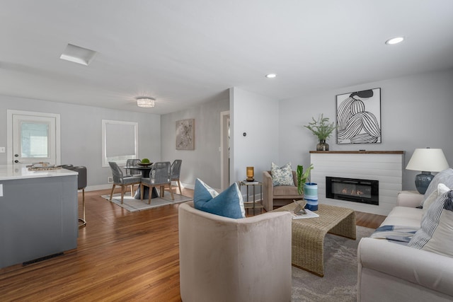 living room with a glass covered fireplace, baseboards, wood finished floors, and recessed lighting