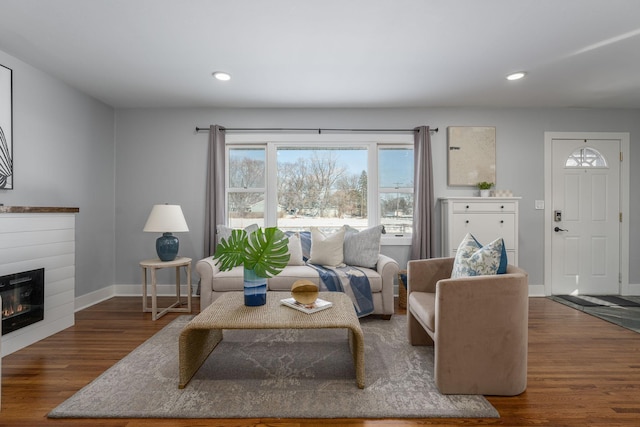 living room featuring a glass covered fireplace, recessed lighting, wood finished floors, and baseboards