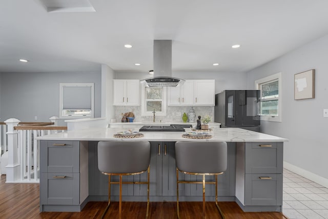 kitchen with island exhaust hood, gray cabinets, white cabinets, fridge, and tasteful backsplash