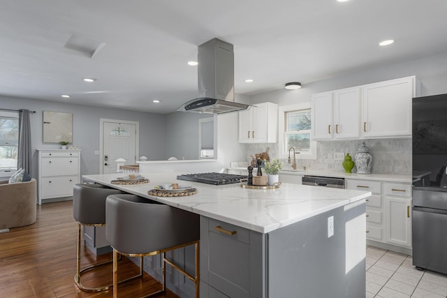 kitchen with white cabinets, a center island, stainless steel appliances, and island range hood