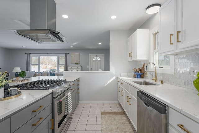 kitchen with light tile patterned floors, decorative backsplash, appliances with stainless steel finishes, island exhaust hood, and a sink