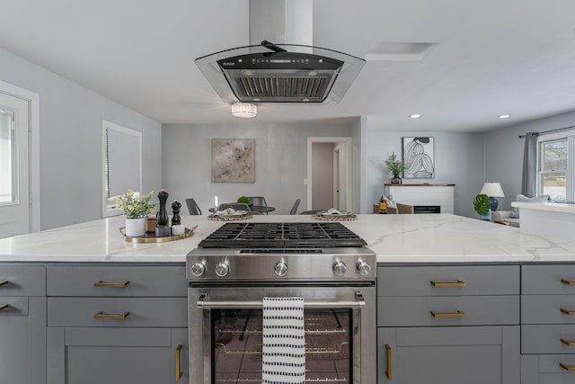 kitchen featuring light stone countertops, stainless steel gas range, open floor plan, and gray cabinets