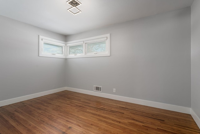 spare room featuring visible vents, baseboards, and wood finished floors