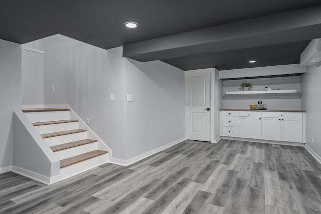 bar with stairs, recessed lighting, wood finished floors, and baseboards