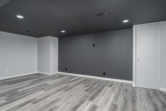 empty room featuring wood finished floors, visible vents, and baseboards