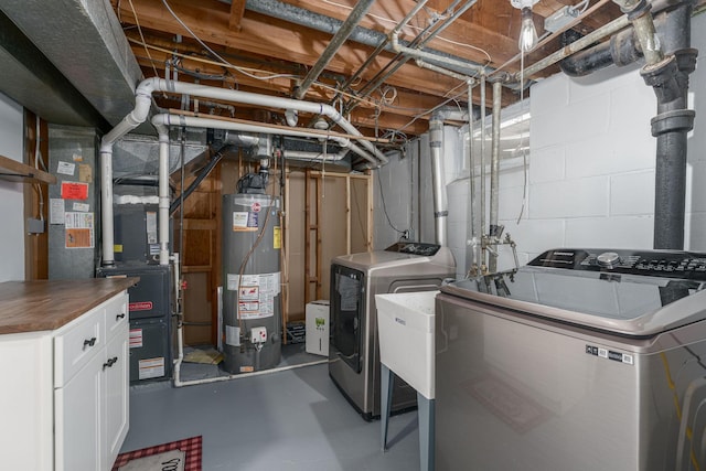 interior space with washing machine and clothes dryer, heating unit, gas water heater, and concrete block wall