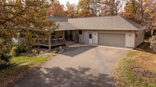 single story home featuring aphalt driveway, an attached garage, a porch, and roof with shingles