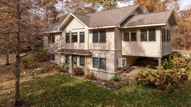 view of front facade with ac unit, a front lawn, and a shingled roof