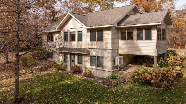 view of front of house featuring ac unit, a front yard, and roof with shingles