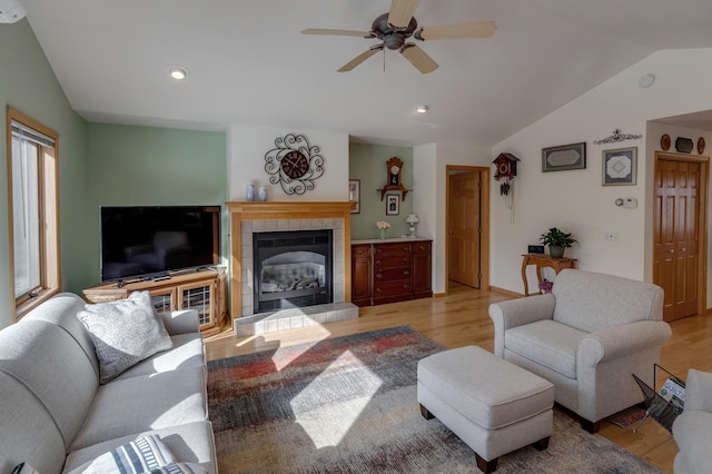 living room with recessed lighting, ceiling fan, vaulted ceiling, light wood-style floors, and a tiled fireplace