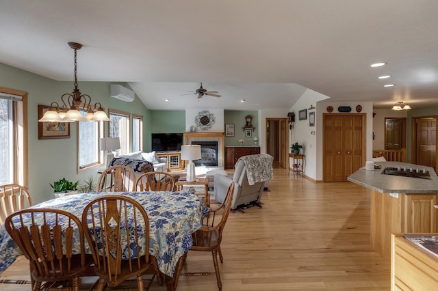 dining area with a tiled fireplace, vaulted ceiling, recessed lighting, light wood-style floors, and a wall mounted AC