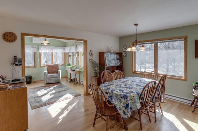 dining space with a chandelier, baseboard heating, and light wood-style flooring